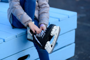 child sitting on blue box and putting on skates