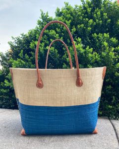 a big straw tote bag with a color blocking effect of royal blue on the bottom half