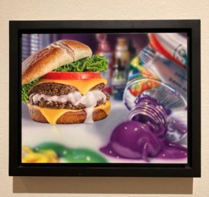 a small painting of a burger and a tube of purple paint