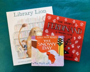 a collage of three books: Library Lion (left), The Story of Ferdinand (right), and The Snowy Day (middle)