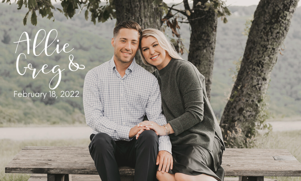 Engagement photo of Greg and Allie on a bench with trees and mountains in the background.