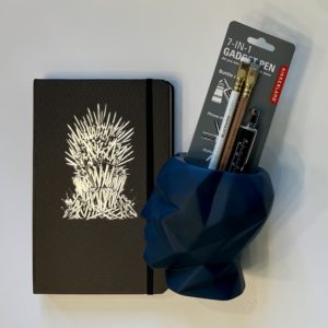 a game of thrones notebook, a blue geometric pencil holder, two pencils and a gadget pen